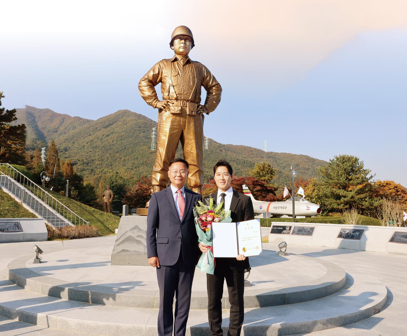 백선엽 장군 동상 앞에서 김재욱 칠곡군수가 최영재 마스터에게 홍보대사 위촉장을 전달하고 기념 촬영을 하고 있다.